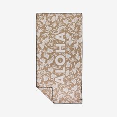 the aloha beach towel in tan and white with floral design on it's front