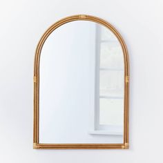 an arched mirror hanging on the wall in front of a white wall with a window