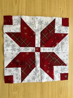 a red and white quilted table topper with snowflakes on the edges