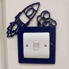 a blue and white light switch cover with an image of a rocket ship on it