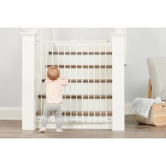 a small child standing in front of a baby gate with his hands on the door