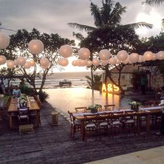 an outdoor dining area with paper lanterns hanging from the ceiling and tables set up for dinner