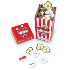 a red and white striped box filled with lots of popcorn next to matching game pieces