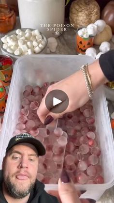 a man is holding up a plastic container filled with candy and marshmallows