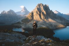 a person standing on top of a mountain with mountains in the background and water below