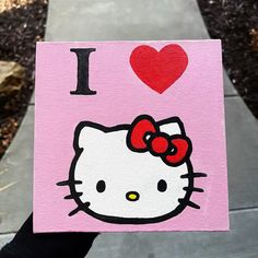 someone holding up a hello kitty card with the word i love it on it and a red heart