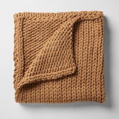 a brown knitted blanket folded on top of a white wall