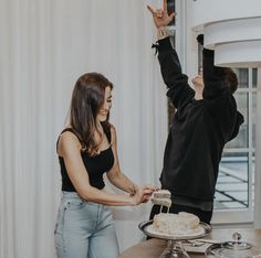 a man and woman reaching for a cake on a table