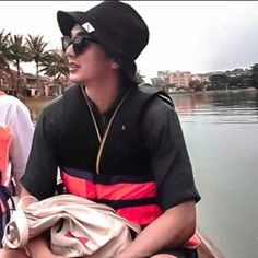 two people sitting in a boat on the water with palm trees behind them and buildings in the background