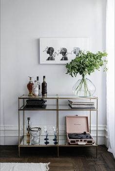 a bar cart with bottles and glasses on it in front of a framed photo above the bar