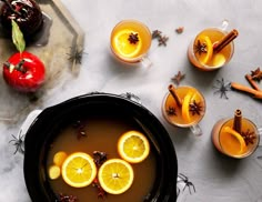 orange slices and cinnamon sticks are garnished with hot cider punch in glasses