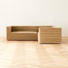 a brown couch sitting on top of a wooden floor next to a white wall in an empty room