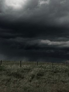 a black and white photo of storm clouds over a field