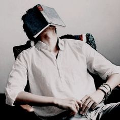 a man sitting in a chair with a hat on top of his head while wearing a pair of bracelets