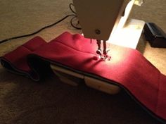 a sewing machine is on top of a red piece of cloth that has been sewn