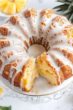 a bundt cake with white icing on a glass plate next to pineapples