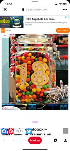 a jar filled with lots of candy sitting on top of a table next to a phone