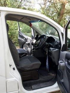 the interior of a small white van with its door open and steering wheel in view