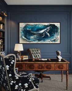 a room with a desk, chair and painting on the wall above it that has a whale swimming in the ocean