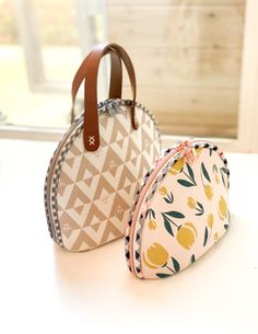 two purses sitting on top of a white table