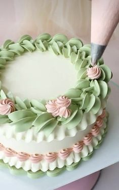 a cake being decorated with green and pink icing