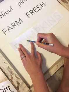 a woman is writing on a sign that says farm fresh with crayon pens