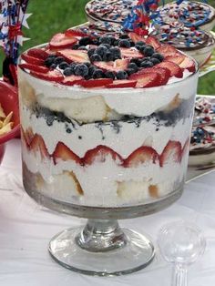 a cake with strawberries and blueberries on top sits on a table next to other desserts