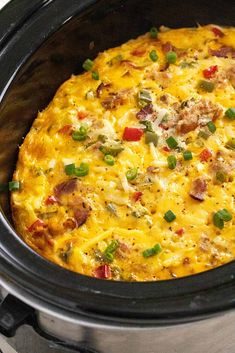 a crock pot filled with an omelet covered in cheese and green onions