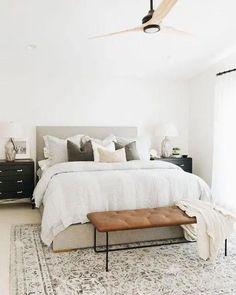 a bedroom with a large bed, white walls and rugs on top of the floor