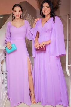 two women in long purple dresses posing for the camera with one holding a blue purse