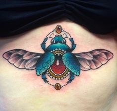 a woman's stomach with a blue and red bee tattoo on her side belly