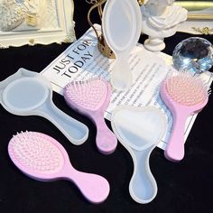 three pink and white hairbrushes sitting on top of a table next to a mirror