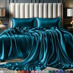 a bed covered in teal satin sheets and pillows