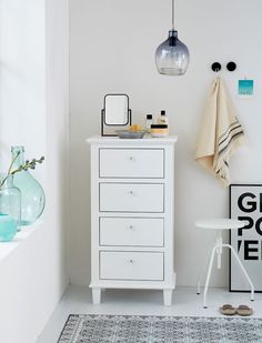 a white dresser sitting next to a window in a room with a rug on the floor