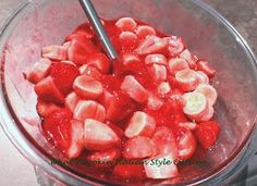 strawberries and bananas are mixed together in a glass bowl with a metal ladle