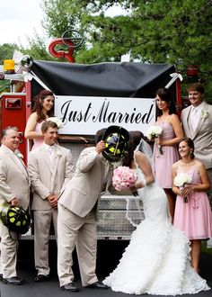 a bride and groom standing in front of a fire truck with their bridal party