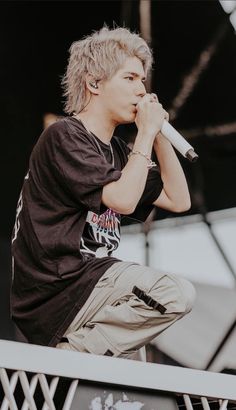 a male in a black shirt is on stage and holding a microphone to his mouth