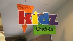 a kidz check - in sign hanging from the ceiling