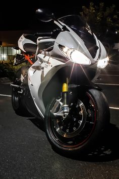 a white motorcycle parked in a parking lot at night