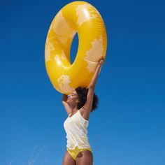 a woman is holding an inflatable object up to her face while standing on the beach