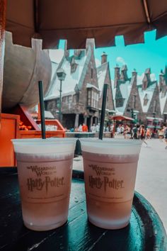 two plastic cups sitting on top of a table in front of a hog potter's house