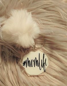 a keychain with the word momlife written on it and a fluffy ball