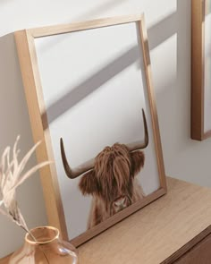 a cow's head is reflected in a mirror next to a vase with dried flowers