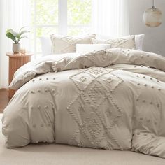 a bed with white comforters and pillows in front of a window, next to a potted plant