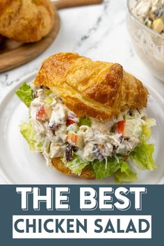 the best chicken salad sandwich is on a white plate with croissants in the background