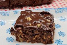 a close up of a piece of cake on a plate with chocolate frosting and nuts