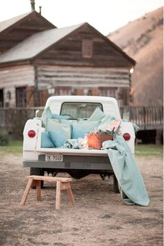 an old pickup truck is parked in the dirt with a blanket on it's bed