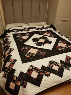 a quilted bedspread with black and pink flowers on it