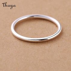 the thin silver ring is sitting on top of a brown surface with words that read thaya