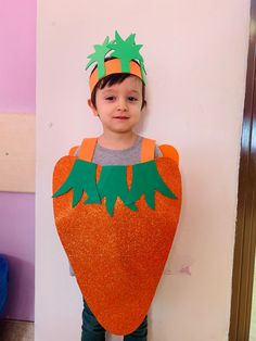 a young boy wearing an orange and green costume